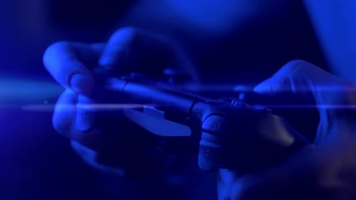 Hands Gaming with a Controller Under Blue Light