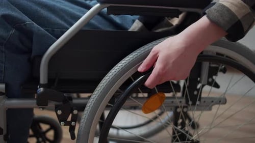 A Disabled Man is Riding on the Wheelchair Through the Room