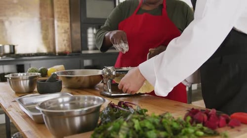 People making pasta in kitchen with fresh vegetables