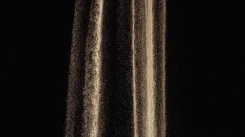 Particles of White Dry Sand are Pouring Down on Black Studio Background