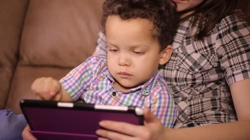 Little Boy Watching a Tablet on Mother's Lap