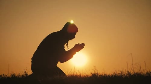 Silhouette Young Man Praying Outside at Beautiful Sunset