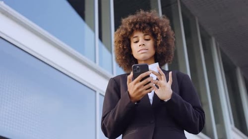 Businesswoman Texting On Smartphone Outside Office