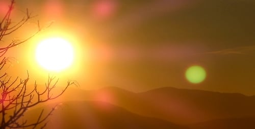 Sunset Behind Mountains with Tree Branches in Foreground