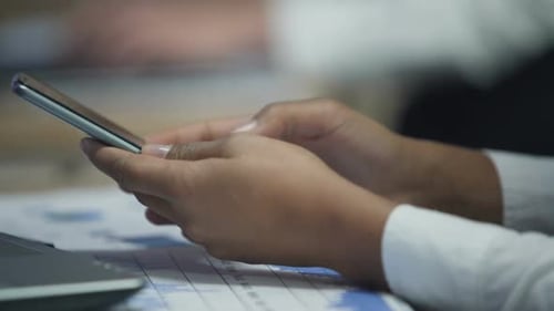 Close Up of Hands Using a Smartphone at Desk