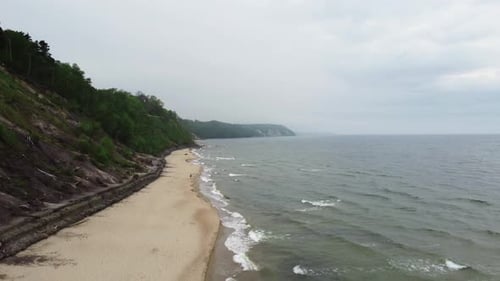 Coast Line with Mountain on One Side and Stormy Ocean on Another is Filmed By Drone