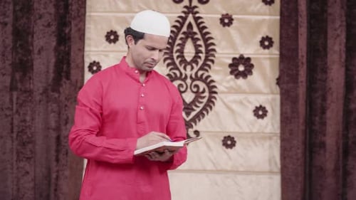 Man Reads Book While Wearing Traditional Muslim Attire