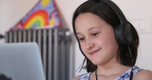 Happy Child Wearing Headphones Looks at Laptop