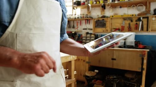 Craftsman Using Tablet in Cluttered Woodworking Shop