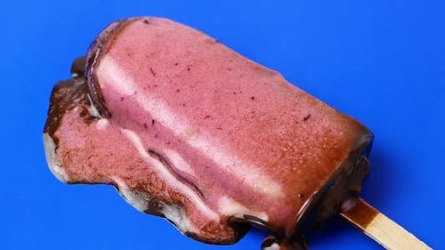 The chocolate ice cream sundae lies on a blue background and melts slowly. 4K video food close-up.