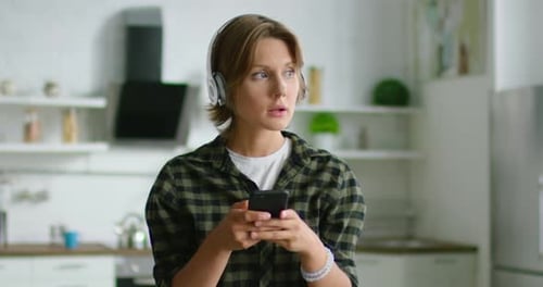 Young Adult Using Smartphone in Modern Kitchen