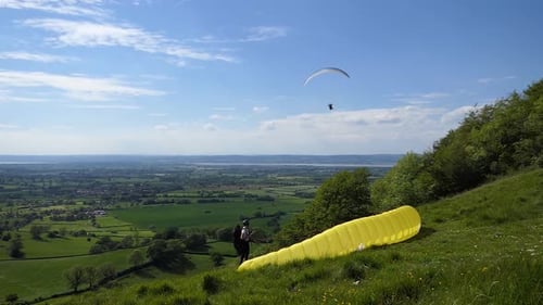 Paraglider Prepares to Launch on Grassy Hillside