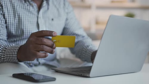 Unrecognizable Senior African American Man Making Online Payment with Credit Card and Laptop at Home