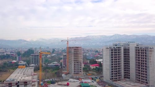 Drone view of construction of multi-storey buildings background of mountains.
