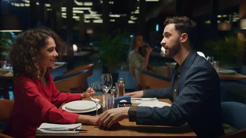 Flirting Couple Hold Hands in Restaurant