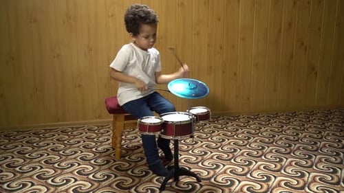 Enthusiastic Young Boy Playing Small Drum Set