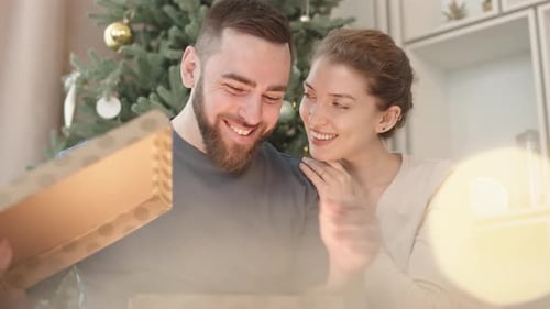 Couple Opening Christmas Present Together by Tree