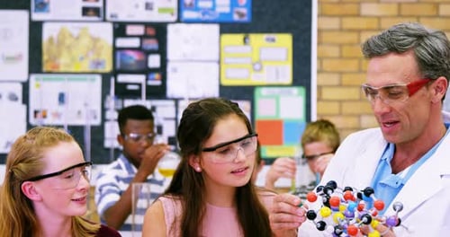 School teacher assisting schoolkids on molecule model 4k