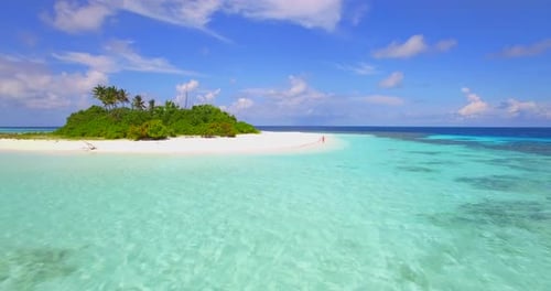 Aerial view of a man walking on the beach around a tiny deserted tropical island.