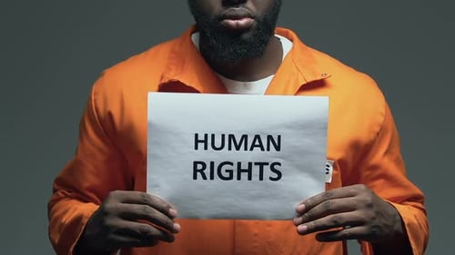 Man in Jumpsuit Holding a Human Rights Sign