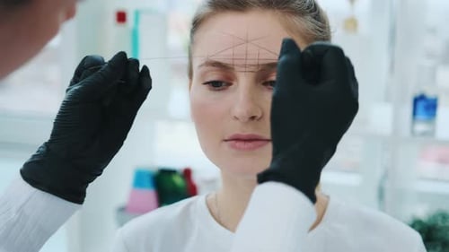 Woman Getting Eyebrows Threaded by Cosmetician