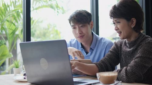 Coworkers Collaborating on Laptop in Bright Cafe