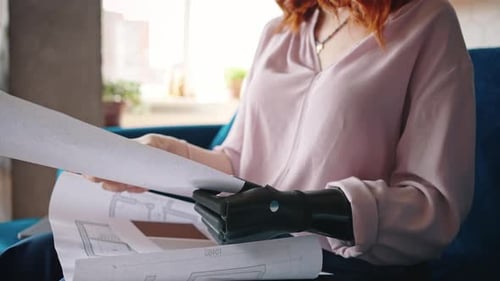 Nahaufnahme einer nicht wiederzuerkennenden Designer-Ingenieurin, die mit einem Roboterarm mit Zeichnungen arbeitet