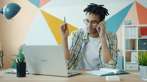 Young Adult Talking on Phone at Desk