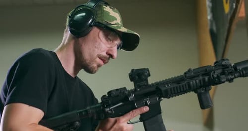 Man Inspects Modern Rifle in Indoor Shooting Range