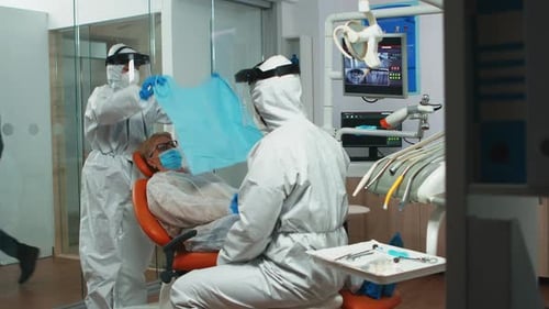 Dentist and Patient in Clinic with Protective Gear