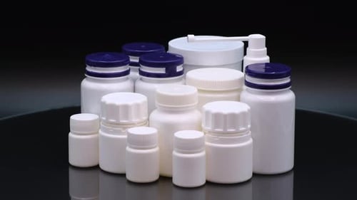 Assorted White Pill Bottles on Black Background
