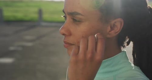 African american woman in sportswear wearing earphones on a sunny day
