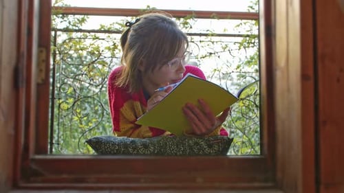 Young Woman Student Learns or Memorizes Doing with a Large Notebook and Pen on a Summer Terrace or