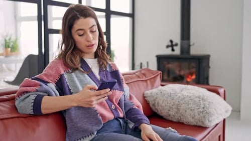 Woman Relaxing on Couch Using Smartphone