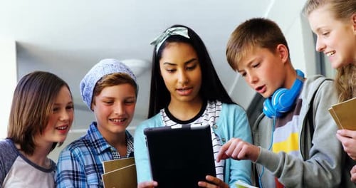 Group of school friends using digital tablet in corridor