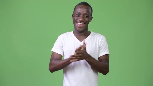 Junger glücklicher afrikanischer Mann klatscht Hände vor grünem Hintergrund