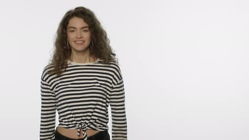 Excited Young Woman Smiles in Front of White Background