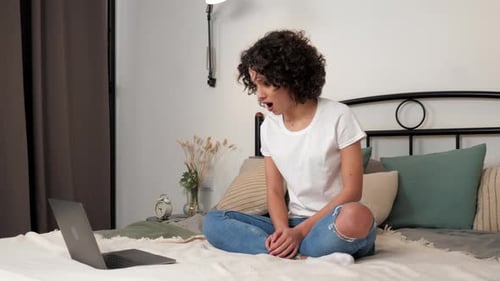 Excited Curly Woman Student Winner Celebrating Admission to University Laptop