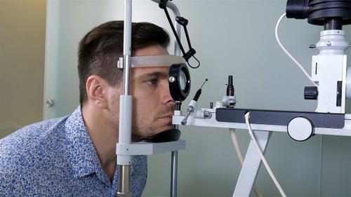 Man in optometrists office checking her vision