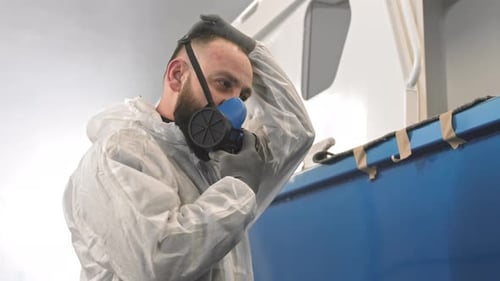Man in Protective Suit Adjusts Full Face Respirator