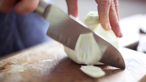 Dicing White Onion on Wooden Board with Knife