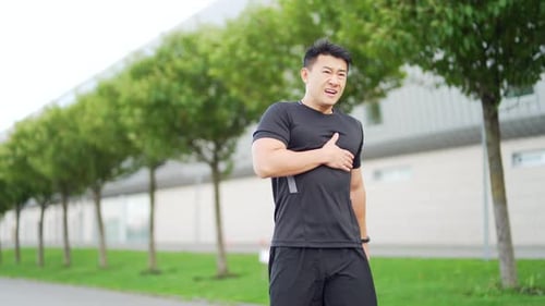 junger erwachsener asiatischer Athlet beim Joggen, Brustverletzung, schwerer Herzinfarkt, Schmerzen
