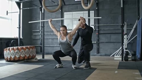 Personal Trainer Helping Woman Doing Barbell Squats