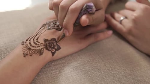 Der Künstler zeichnet ein Mehendi-Muster auf die Hände und trägt Paste aus der Tube auf, Nahaufnahme