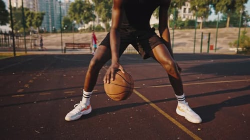 Closeup of a Young Black Basketball Player Dribbling the Ball Across the Field