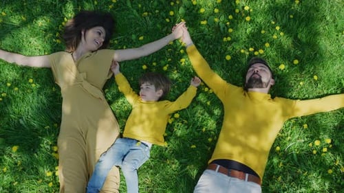 Family Lies Together on Grassy Spring Meadow