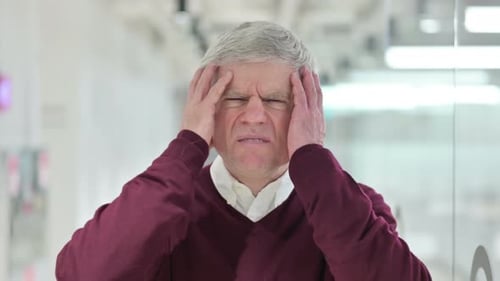 Frustrated Older Man Massaging Temples Due to Headache