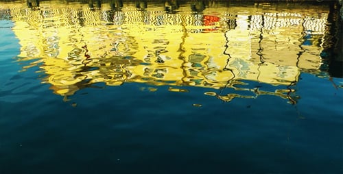 Yellow Building Reflection on Rippling Water Surface
