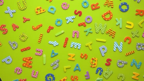 Colorful Magnetic, Plastic and Paper Alphabet Letters Placed Randomly on Green Background