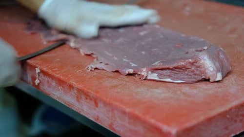 Chef Slicing Meat Very Thinly on Cutting Board